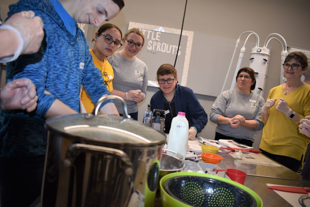Teens cooking with cooking pot and other cooking utensils on the foreground