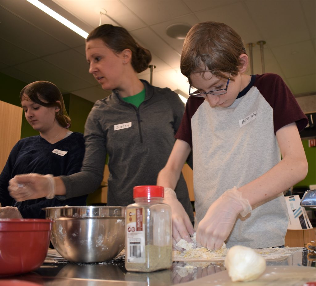 Boy in gray and maroon t-shirt kneading dough