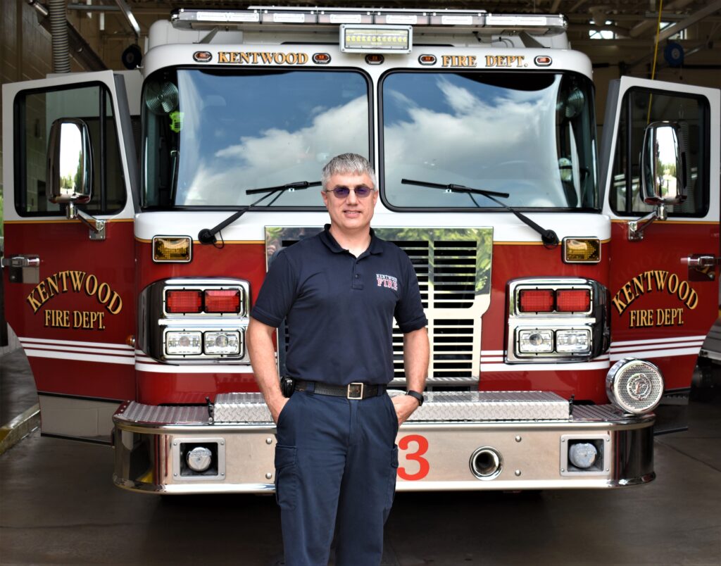 Man dressed in all blue standing in front of a red fire engine