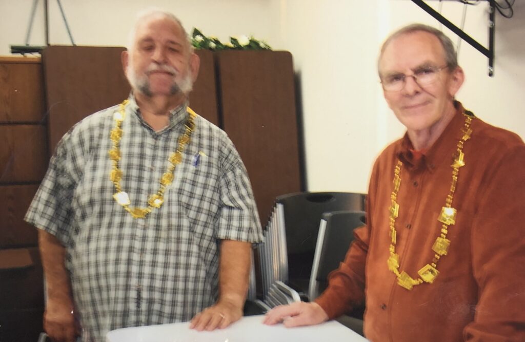 Photo of Marty and another man smiling. They both have golden beads around their neck