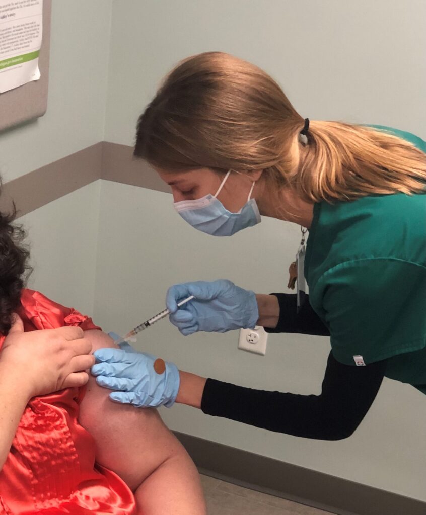 Nurse giving vaccine into woman's arm