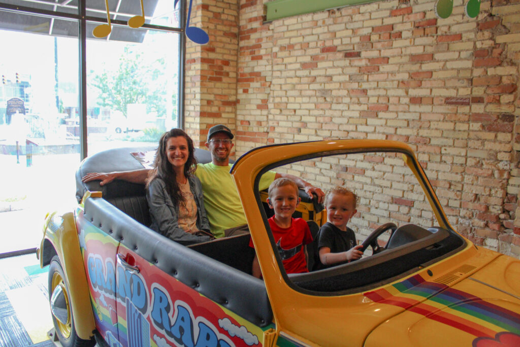 Family og four sitting in a yellow convertible