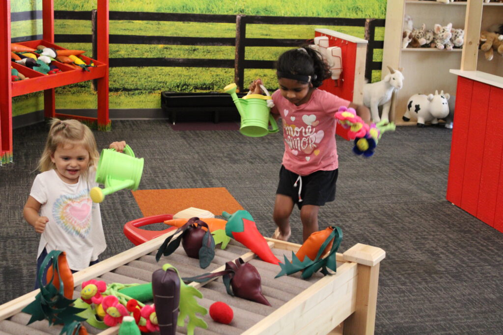 Two girls playing at a farm play table