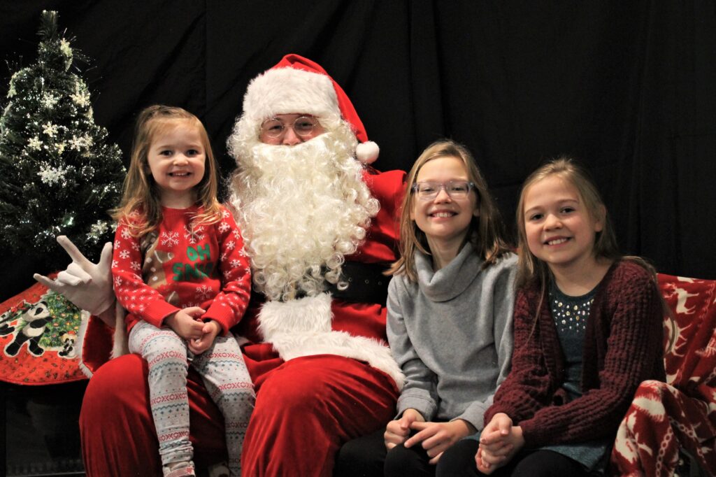 Three young girls visit with Santa