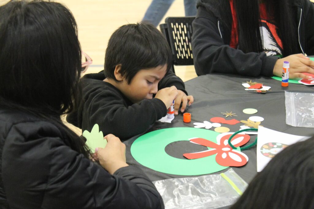 Young boy sitting at a table doing a wreath craft
