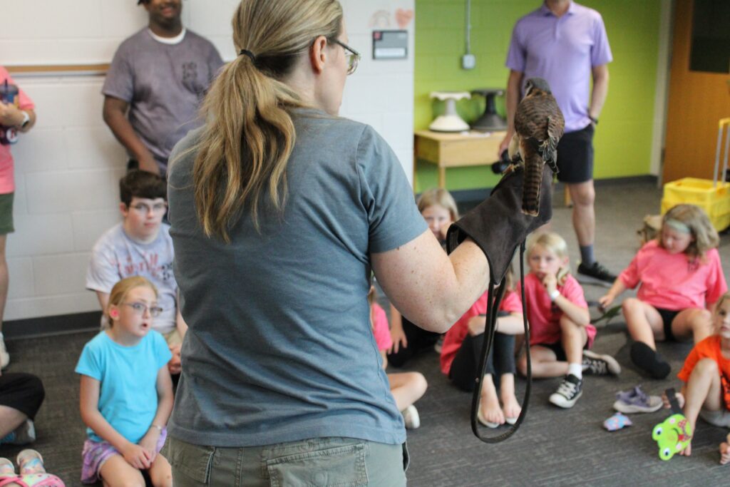 Blandford Nature Center staff holding a bird on her hand. She is showing the kids