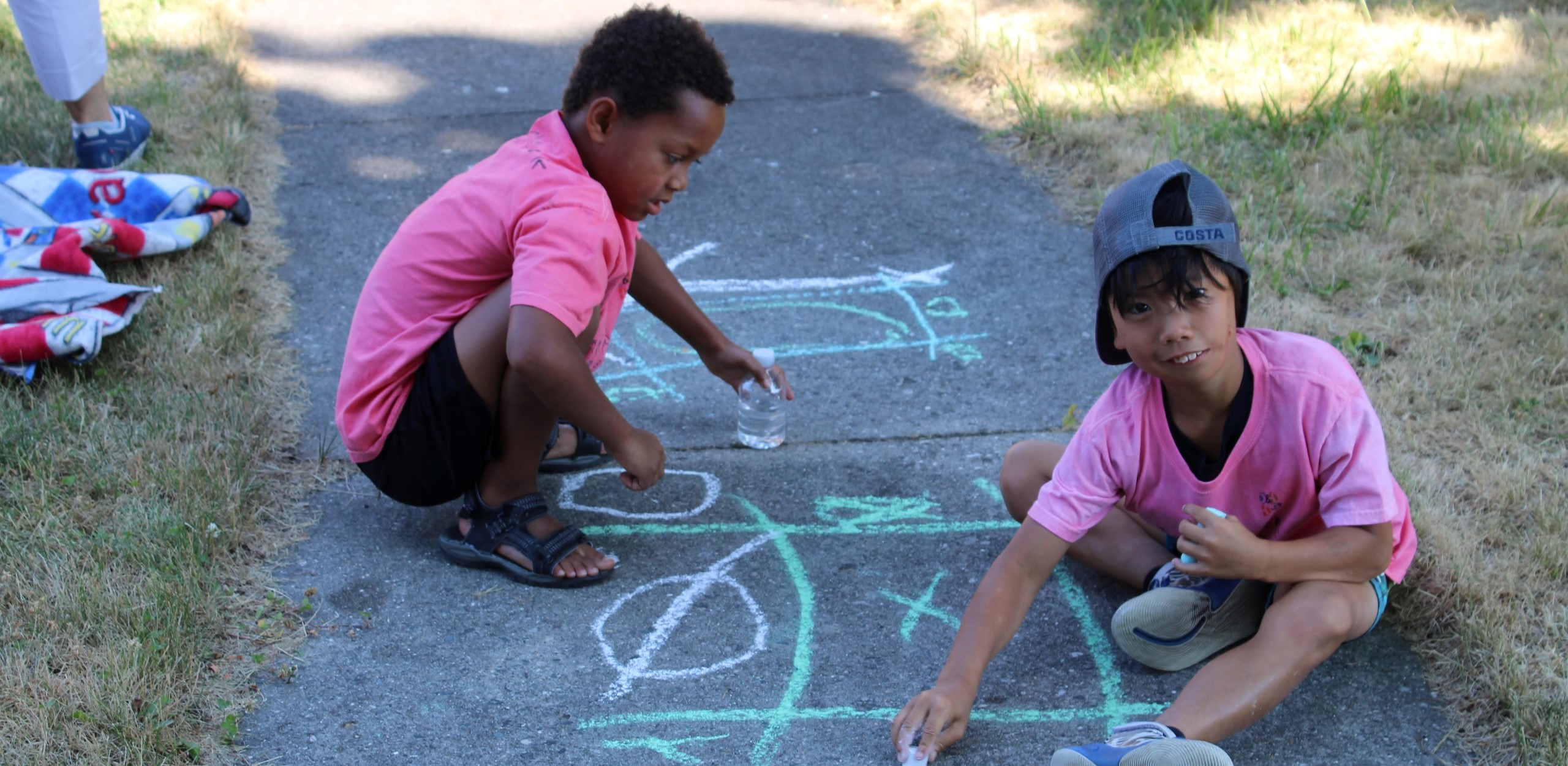 Two boys outside drawing with chalk