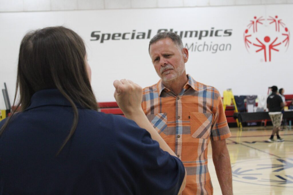 man in a plaid shirt. He is talking to a woman with her back to the camera. They are using sign language