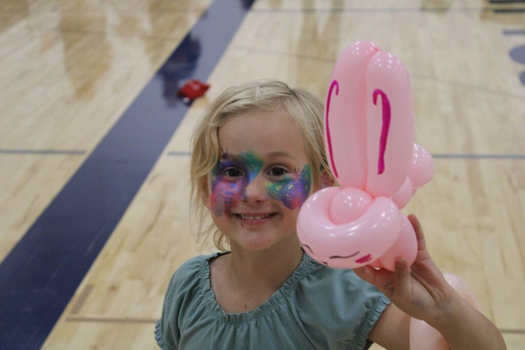 Little girl with a painted face and a balloon animal