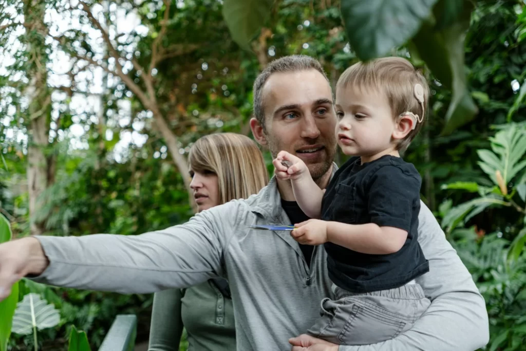 A man holding a young boy. He is pointing to something off camera